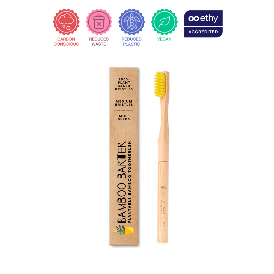 A bamboo toothbrush with yellow bristles outside the packaging.